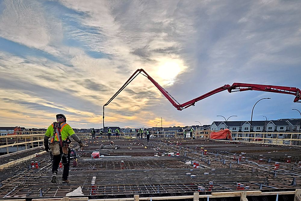 A pump boom over a tied deck at first light, crew spotting the pour